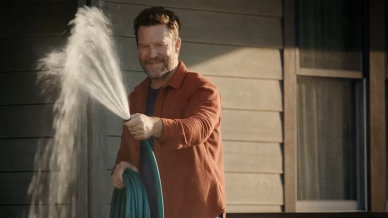 Still from the Pippin concept film (spec, AI-generated): a man sprays water with a garden hose in front of his house.